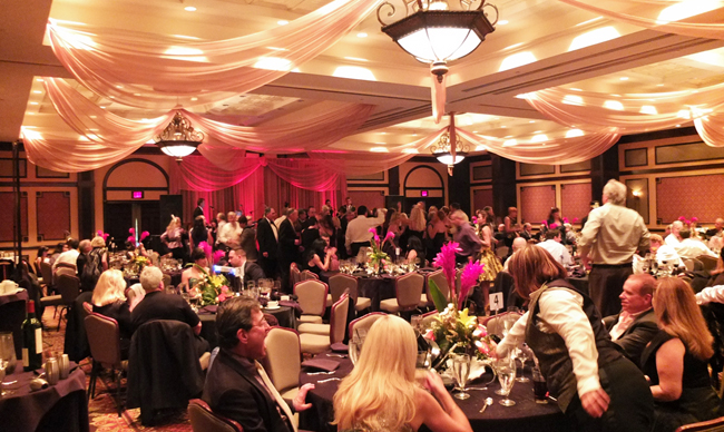 Custom ceiling draping and backdrop in gold chiffon with red LED up-lights for a New Year's Eve party at Hammock Beach Resort in Palm Coast, FL. Photo and drapes by W Drapings.