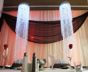 Custom backdrop in ivory and brown chiffon featuring a set of decorative crystal chandeliers. Photo and drapes by W Drapings.